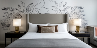 Straight on view of a bed and side tables with artwork on the wall