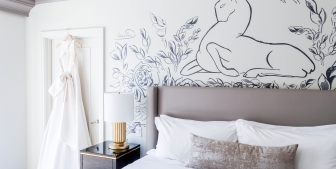 A hotel room with a large king bed with white linens and wall art.